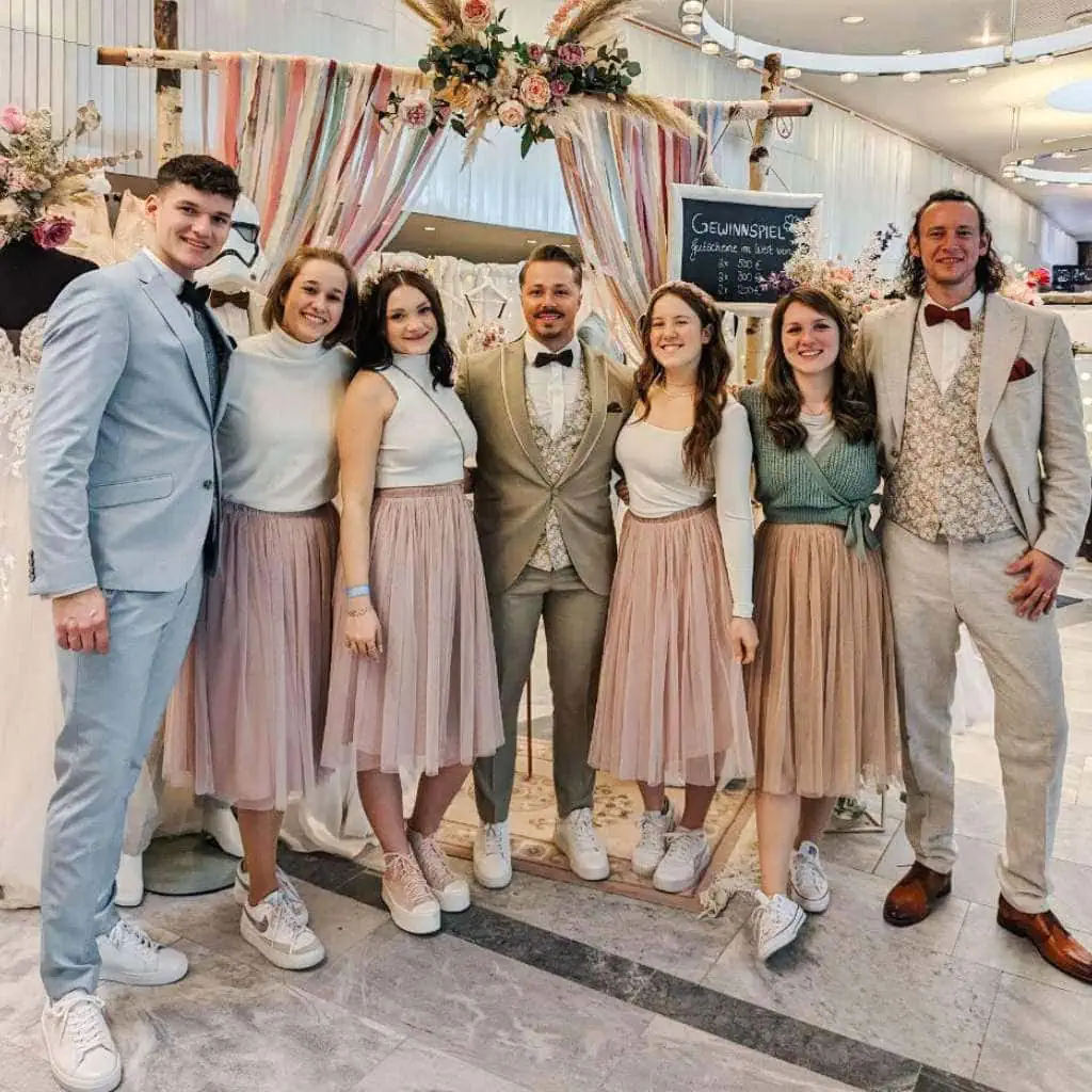 Hochzeitsmesse Crew Zaubermomente vor Brautkleidern und Hochzeitsanzügen Hochzeitsdekoration und einem Traubogen